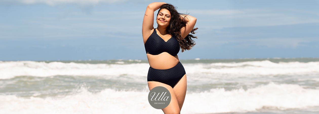 Eine junge, mollige Frau steht am Strand in der Sonne und trägt Bikini Monaco von Ulla