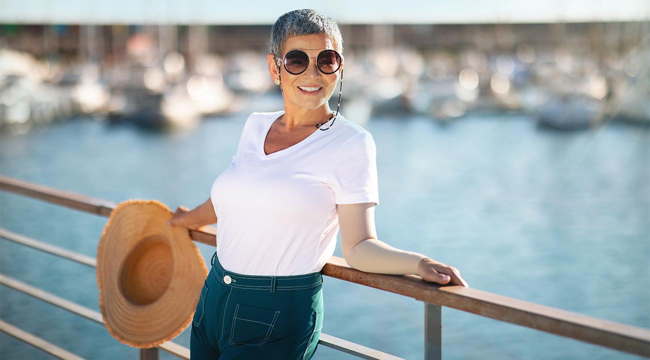 Frau im Sommer, leicht bekleidet mit beigem Armstrumpf am Pier
